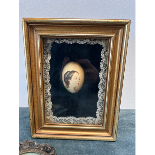 296 - Cased painted egg and reproduction of Mona Lisa in brass frame