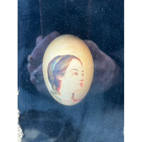 296 - Cased painted egg and reproduction of Mona Lisa in brass frame