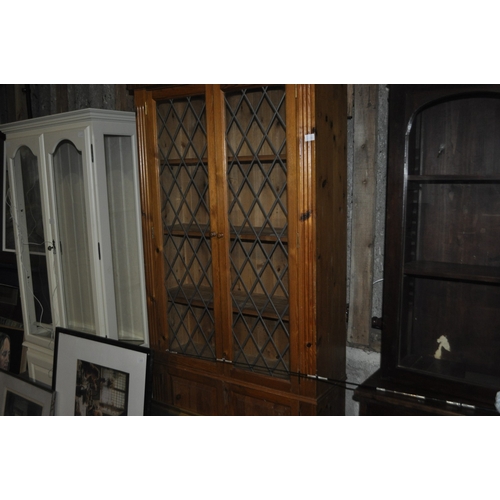 1215 - A VINTAGE PINE LEADED GLASS DISPLAY CABINET WITH FOUR SHELVES OVER TWO DOORS AND DETAILED BLOCK CORN... 