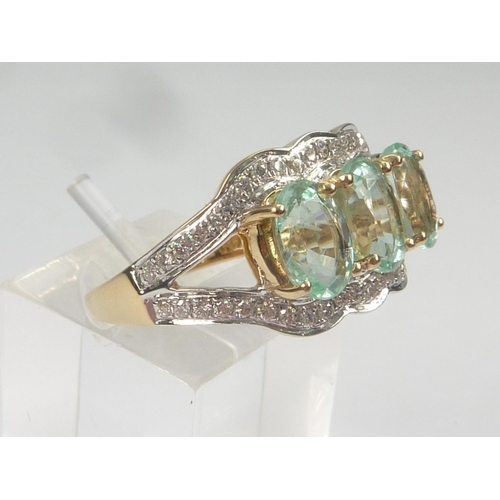 30 - Dress ring with three oval aquamarines within a border and shoulders with diamonds. Size 'L 1/2'.