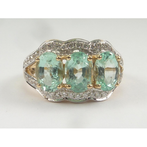 30 - Dress ring with three oval aquamarines within a border and shoulders with diamonds. Size 'L 1/2'.