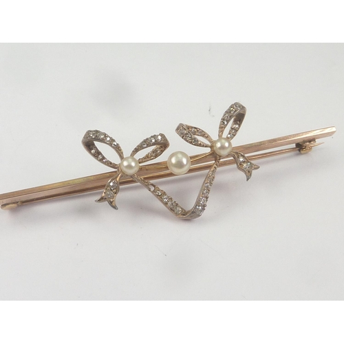 42 - Edwardian gold brooch with two diamond and pearl set bows upon a bar, probably 18ct.