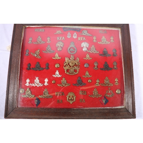 373 - Framed display of approximately 60 Royal Artillery cap badges, buttons, shoulder titles, cloths, col... 