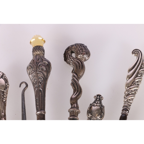 153 - Sixteen silver handled button hooks, one with lion head finial, one with stork head set with ruby ey... 