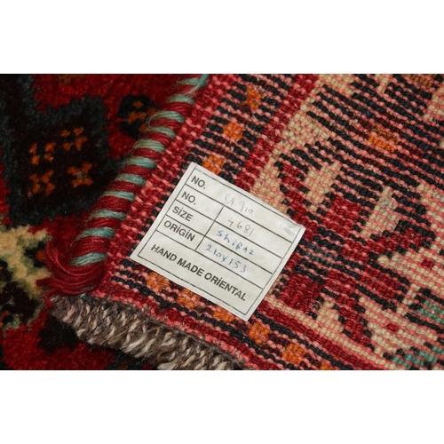 497 - Eastern red ground fringed rug with multiple gul field, 215cm x 115cm 