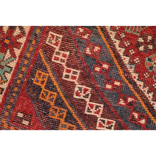 497 - Eastern red ground fringed rug with multiple gul field, 215cm x 115cm 