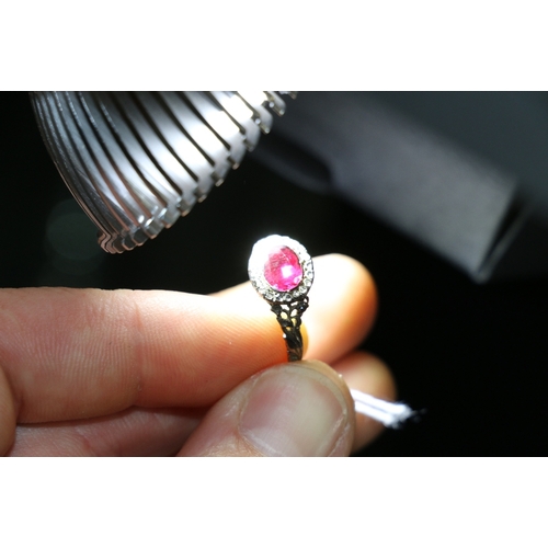 80 - Antique dress ring set with central oval pink red stone, possibly a ruby, encircled by diamond chips... 