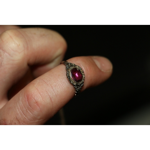 80 - Antique dress ring set with central oval pink red stone, possibly a ruby, encircled by diamond chips... 