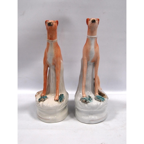 203 - Pair of Staffordshire seated greyhounds, each with a hare at their feet, 21.5cm high.