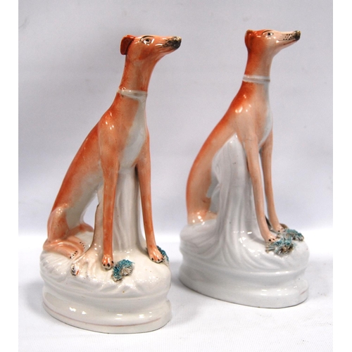 203 - Pair of Staffordshire seated greyhounds, each with a hare at their feet, 21.5cm high.