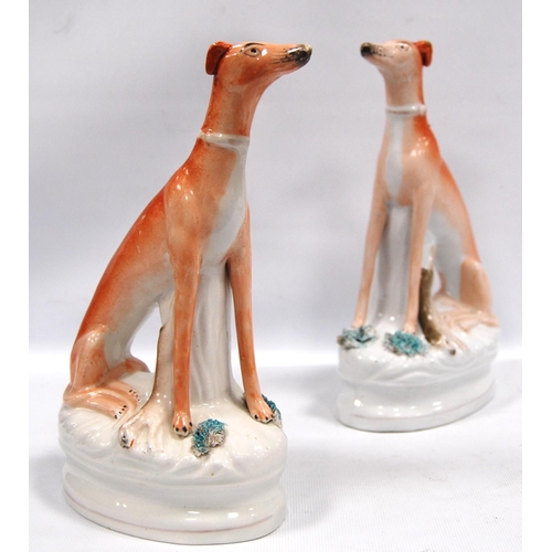 203 - Pair of Staffordshire seated greyhounds, each with a hare at their feet, 21.5cm high.