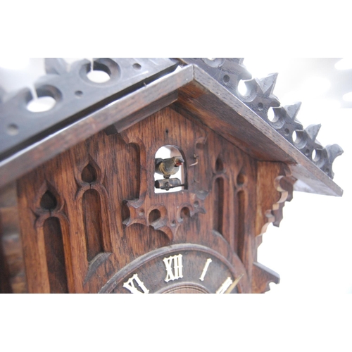 222 - Black Forest cuckoo clock with fretwork pediment over turned face, Roman numerals, flanked by carved... 