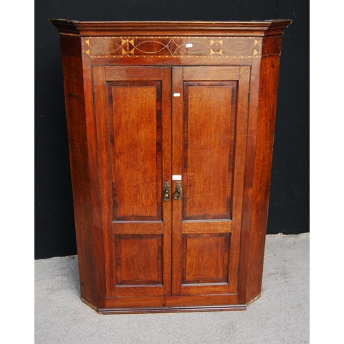 351 - Georgian mahogany and oak corner cupboard, the projected moulded cornice over floral frieze and pane... 