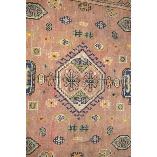 355 - Eastern rug with triple medallions over pink ground, rosettes and border, 157cm x 115cm.