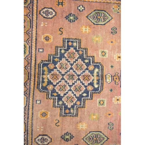 355 - Eastern rug with triple medallions over pink ground, rosettes and border, 157cm x 115cm.