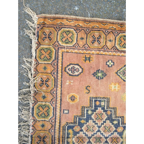 355 - Eastern rug with triple medallions over pink ground, rosettes and border, 157cm x 115cm.