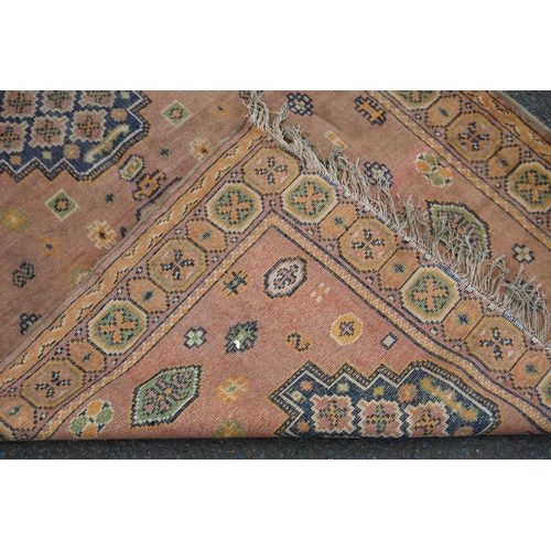 355 - Eastern rug with triple medallions over pink ground, rosettes and border, 157cm x 115cm.