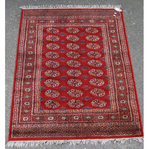 359 - Afghan style machine rug with three rows of nine guls over red ground and border, 173cm x 130cm.