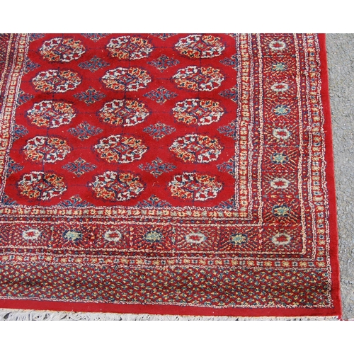 359 - Afghan style machine rug with three rows of nine guls over red ground and border, 173cm x 130cm.