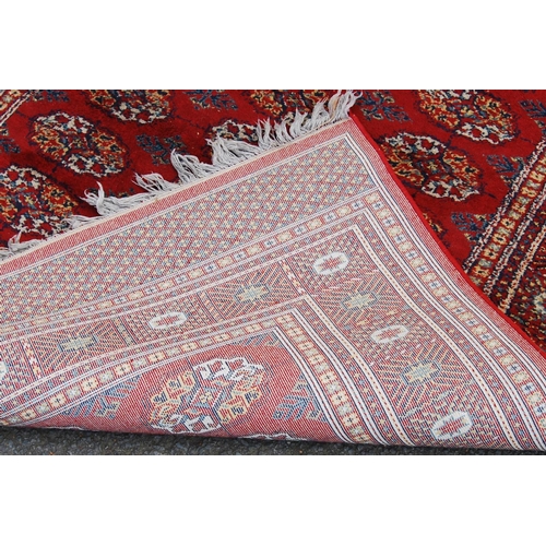 359 - Afghan style machine rug with three rows of nine guls over red ground and border, 173cm x 130cm.