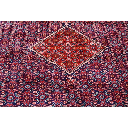 389 - Persian carpet with central red diamond over blue ground, all over geometric floral design, spandrel... 