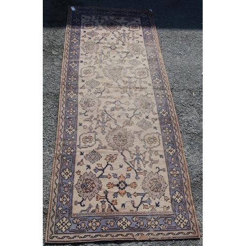 392 - Ushak design rug with foliate design over worn cream ground and faded blue border, 315cm x 115cm.