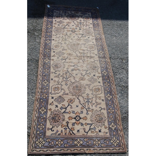 392 - Ushak design rug with foliate design over worn cream ground and faded blue border, 315cm x 115cm.