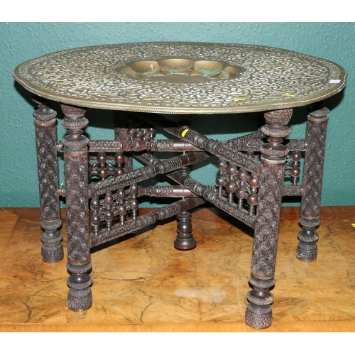 552 - Repoussé brass charger top table upon carved indo-persian folding base, 80cm diameter