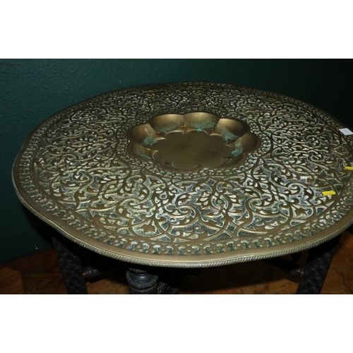 552 - Repoussé brass charger top table upon carved indo-persian folding base, 80cm diameter