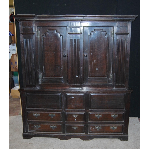 370 - Oak hall cupboard, the projected moulded cornice over panelled doors, fluted columns, stepped base, ... 