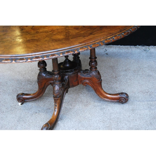 377 - Victorian walnut loo table with oval inlaid top, floral carved moulding, raised on baluster quad col... 