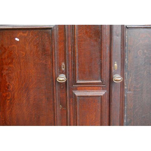 384 - Georgian oak hall cabinet, the projected moulded cornice over panelled doors over stepped base with ... 