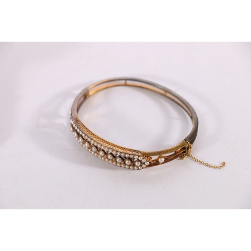 85 - Victorian unhallmarked yellow metal bangle set with seed pearls, 16.2g gross in Sorley of Glasgow fi... 