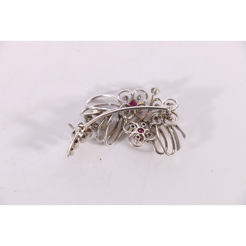 87 - Unhallmarked white metal openwork floral spray brooch set with three pink rubies and twenty-three sm... 