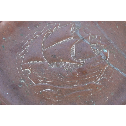 233 - An Arts & Crafts Newlyn School repousse copper charger decorated to the centre with galleon sail... 