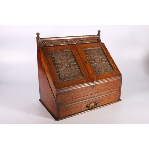 310 - Late Victorian carved oak sloped-fronted table-top stationary box with envelope rack, pen tray, inkw... 