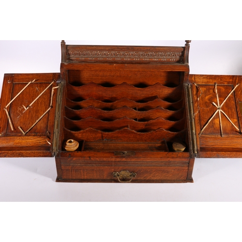 310 - Late Victorian carved oak sloped-fronted table-top stationary box with envelope rack, pen tray, inkw... 