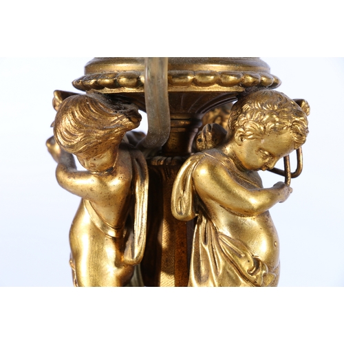 313 - Pair of gilded metal candlestick table lamps, the ornate stems supported by a trio of cherub musicia... 