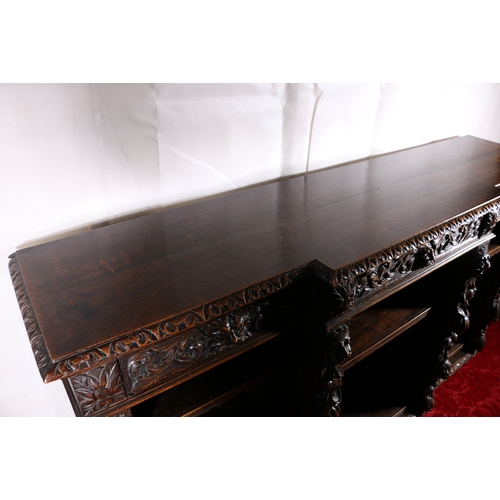 441 - Antique heavily carved oak break front bookcase, frieze fitted with three drawers above carved lion ... 