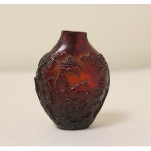 172 - Two antique Chinese snuff bottles to include a dark red carved amber bottle decorated with reliefs o... 