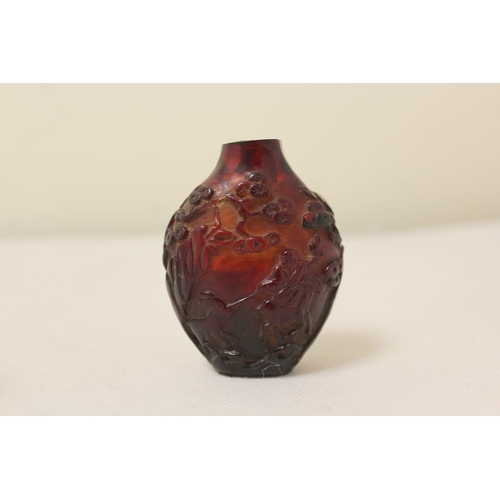 172 - Two antique Chinese snuff bottles to include a dark red carved amber bottle decorated with reliefs o... 