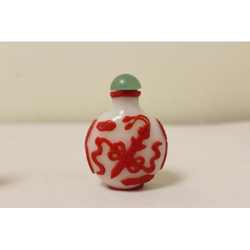 173 - Two Chinese glass snuff bottles to include a red glass overlay bottle of spherical form decorated wi... 