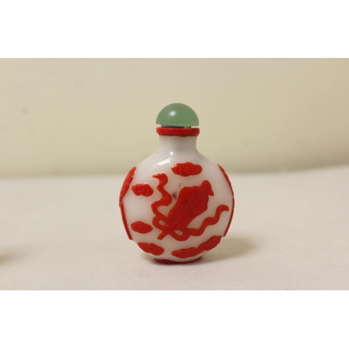 173 - Two Chinese glass snuff bottles to include a red glass overlay bottle of spherical form decorated wi... 