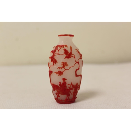 173 - Two Chinese glass snuff bottles to include a red glass overlay bottle of spherical form decorated wi... 