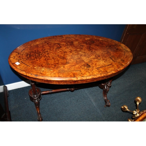 729 - Victorian walnut and inlaid oval table, raised on castors.