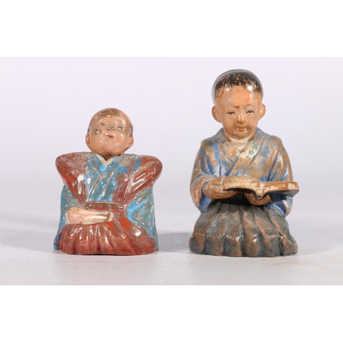 449 - Two Japanese painted ceramic figures, one of a kneeling boy reading a book, the other of a seated fi... 