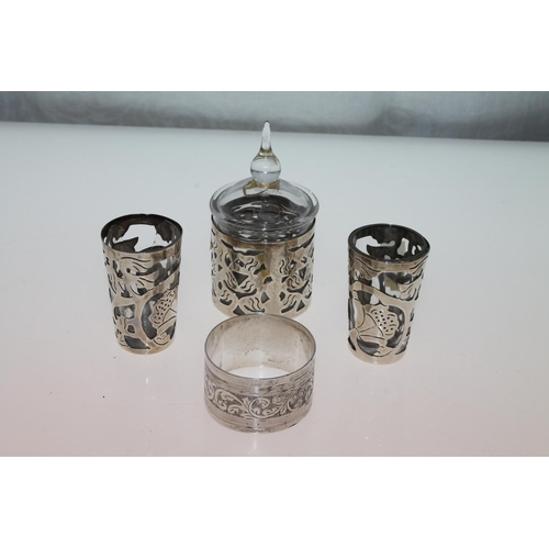 460 - Silver foliate napkin ring, two silver shot glasses, and a silver and glass pot.