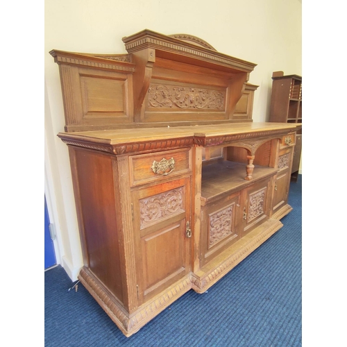 561 - Late 19th century light oak sideboard, the arched raised back with dentil cornice and foliate carved... 