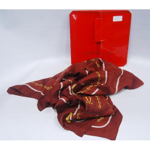 136 - Must de Cartier silk scarf on a claret ground, 83cm x 79.5cm, with original sleeve.