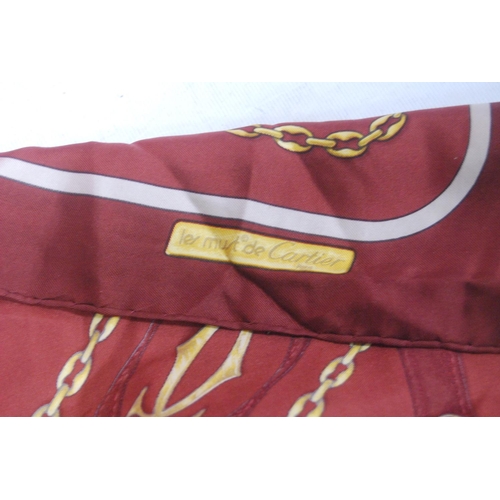 136 - Must de Cartier silk scarf on a claret ground, 83cm x 79.5cm, with original sleeve.